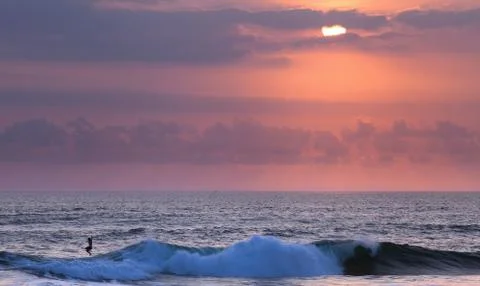 Surfer at sunset in Ocean Wave Stock Photos