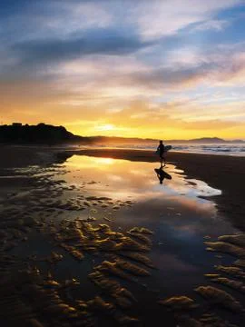 Surfer at sunset with reflection on puddle Stock Photos