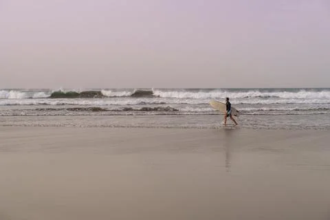 Surfer with surfboard in hands going through beautiful sand beach in Lanzarote Stock Photos