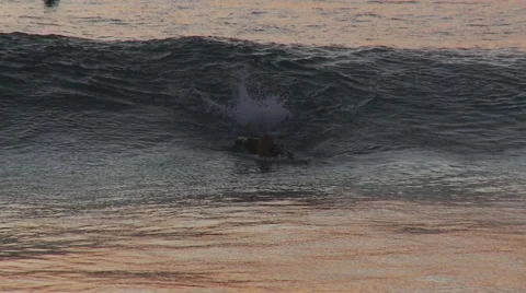 Surfer surfs a wave at sunset Stock Footage 64220773