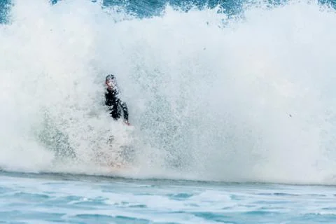 Surfer swallowed by a big wave on a beach on the north coast of Spain Stock Photos