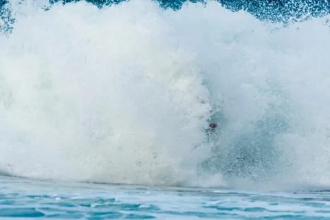 Surfer swallowed by a big wave on a beach on the north coast of Spain Stock Photos