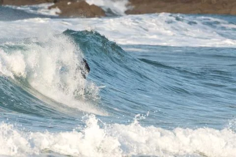 Surfer swallowed by a big wave on a beach on the north coast of Spain Stock Photos