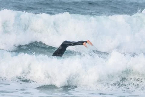 Surfer swallowed by a big wave on a beach on the north coast of Spain Stock Photos