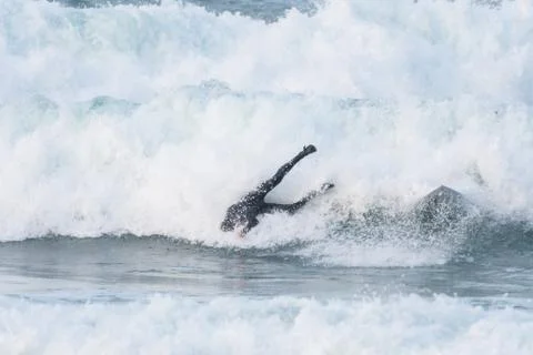 Surfer swallowed by a big wave on a beach on the north coast of Spain Stock Photos