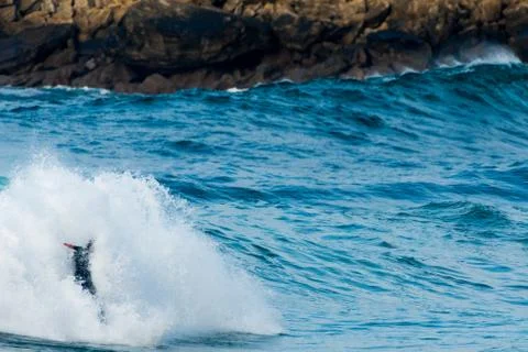 Surfer swallowed by a big wave on a beach on the north coast of Spain Stock Photos