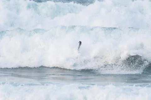 Surfer swallowed by a big wave on a beach on the north coast of Spain Stock Photos