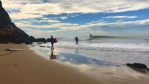 A surfer taking a wave and people around and on the beach watching Stock-Footage 101471332