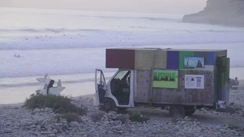 Surfer van on the shore on cloudy weather with surfers on the background Stock Footage 239452081