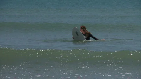 Surfer waiting for a surf-able wave and paddles towards the camera as a little  Stock Footage 559331