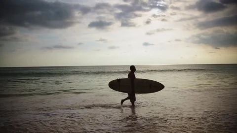 Surfer walk at sunset on the beach Stock Footage 75465023