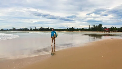 A surfer walking along the beach with a board in his hands Stock-Footage 101471333