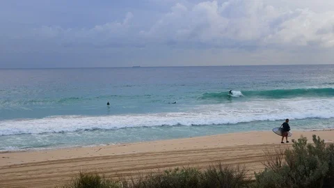 Surfer walking up the beach on a cloudy day Stock Footage 91504535