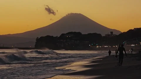 Surfer walking on the beach with mount fuji at sunset Stock Footage 324875532