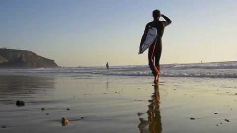 Surfer walking on the beach an start surfing in golden hour Video stock 79485065