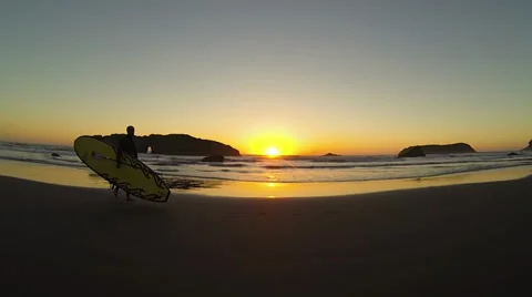 Surfer walking on the beach at sunset Stock Footage 37733336