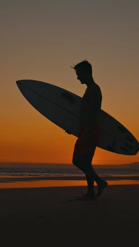 Surfer walking on the beach at sunset Stock Footage 329136107