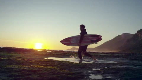 Surfer walking in a puddle on the beach Stock Footage 279002353