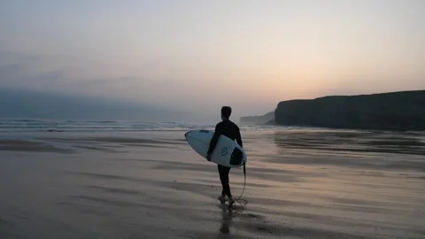 Surfer walking to surf in first light of sunrise 스톡 동영상 274901265
