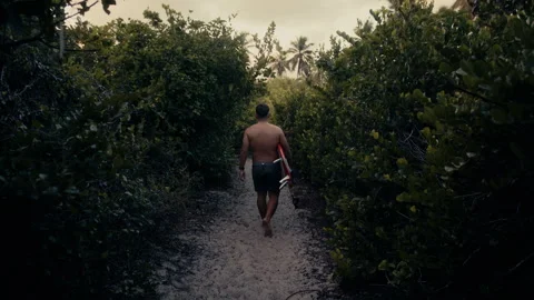 Surfer walking through green path Stock Footage 307313680