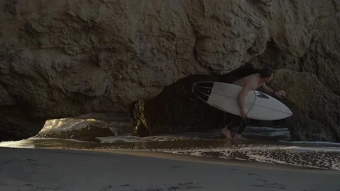 Surfer Walking Under Cliff Rocks Stock Footage