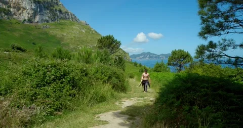 A surfer walks along a picturesque path with his surfboard. Stock Footage 343672834