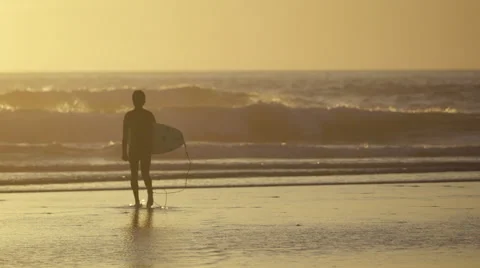 Surfer walks on beach during sunset Video stock 56658052