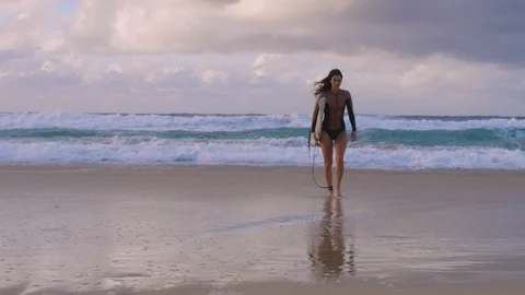 Surfer walks toward camera along the wet sand with leash and board Видео 102149169
