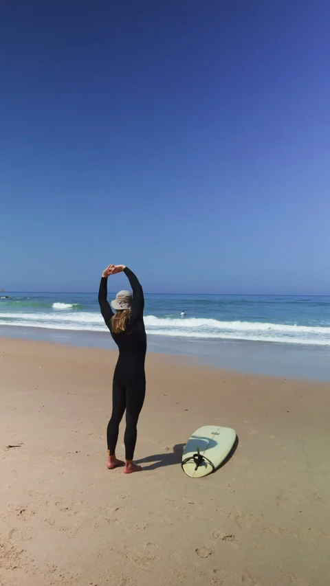 Surfer Warming Up and Stretching on Sunny Beach Stock Footage 344946709