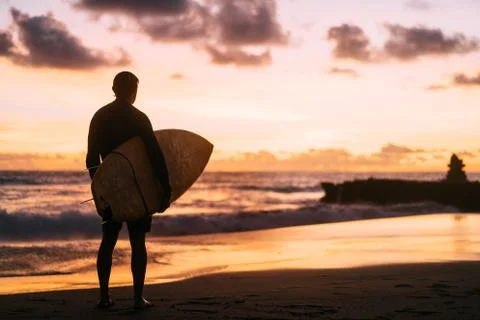 Surfer watching the sunset near the ocean Stock Photos