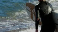 Surfer In Wet Suit Runs Into Surf And Paddles Out In Slow Motion. Stock Footage