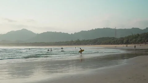 Surfers Approaching Gentle Waves on Tropical Shore at Red Island Beach Stock Footage 335379635