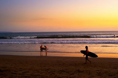 Surfers on beach at sunset Stock Photos