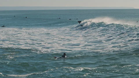 Surfers catching Atlantic Ocean waves on a beautiful sunny day Stock Footage 130627391