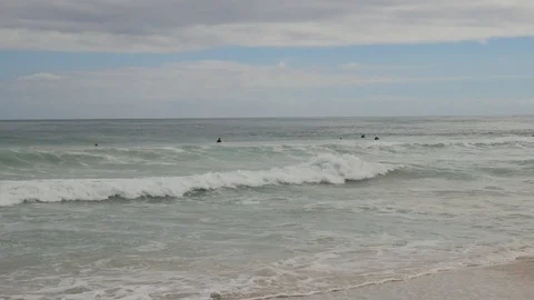 Surfers catching waves at a beach on an overcast day Australia Vídeo Stock 107584013