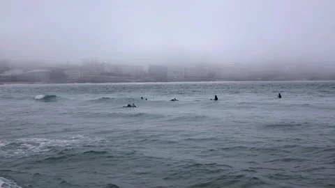 Surfers learn to surf a board in the ocean, during heavy fog against the Stock Footage 232396068