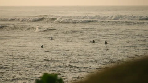 Surfers paddle out to catch waves at dawn. Group rides ocean swells, balances on Stock Footage 261029754