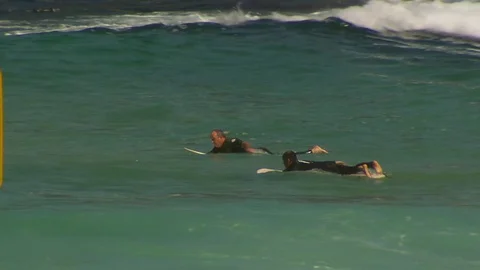 Surfers paddle through the ocean in dangerous currents Stock Footage 76002406