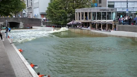 Surfers ride artificial waves in urban pool near café terrace 스톡 동영상 319910741