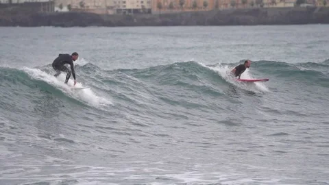 Surfers ride waves in slow motion at Las Canteras Beach Stock Footage 233254292