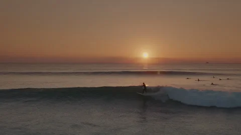 Surfers riding blue ocean waves at golden sunset in Portugal. Stock Footage 285722012