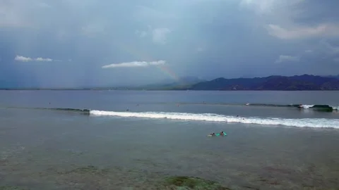 Surfers riding ocean wave under vibrant rainbow. Lovely aerial view drone Stock Footage 340199336