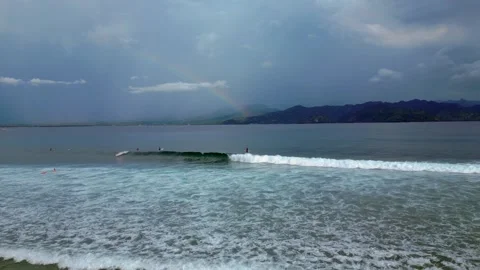 Surfers riding ocean wave under vibrant rainbow. Great aerial view drone Stock Footage 340199593