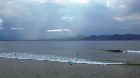 Surfers riding ocean wave under vibrant rainbow. Smooth aerial view drone Stock Footage 340199796