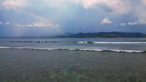 Surfers riding ocean wave under vibrant rainbow. Unique aerial view drone Stock Footage 340199921