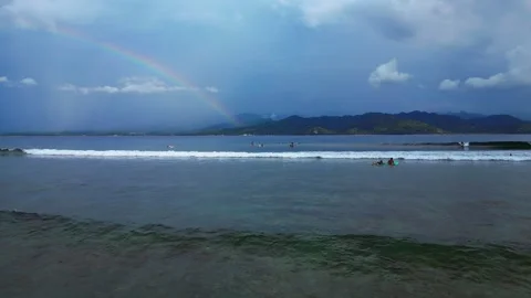 Surfers riding ocean wave under vibrant rainbow. Best aerial view drone Stock Footage 340199931