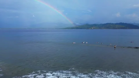 Surfers riding ocean wave under vibrant rainbow. Great aerial view drone Stock Footage 344587796