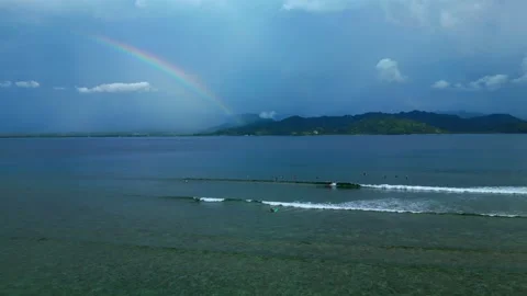 Surfers riding ocean wave under vibrant rainbow. Gorgeous aerial view drone 스톡 동영상 344607182