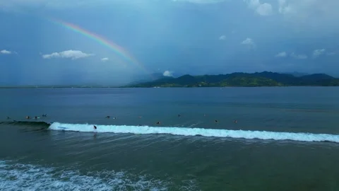 Surfers riding ocean wave under vibrant rainbow. Fantastic aerial view drone 스톡 동영상 344607811