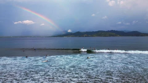 Surfers riding ocean wave under vibrant rainbow. Perfect aerial view drone Stock Footage 344614384
